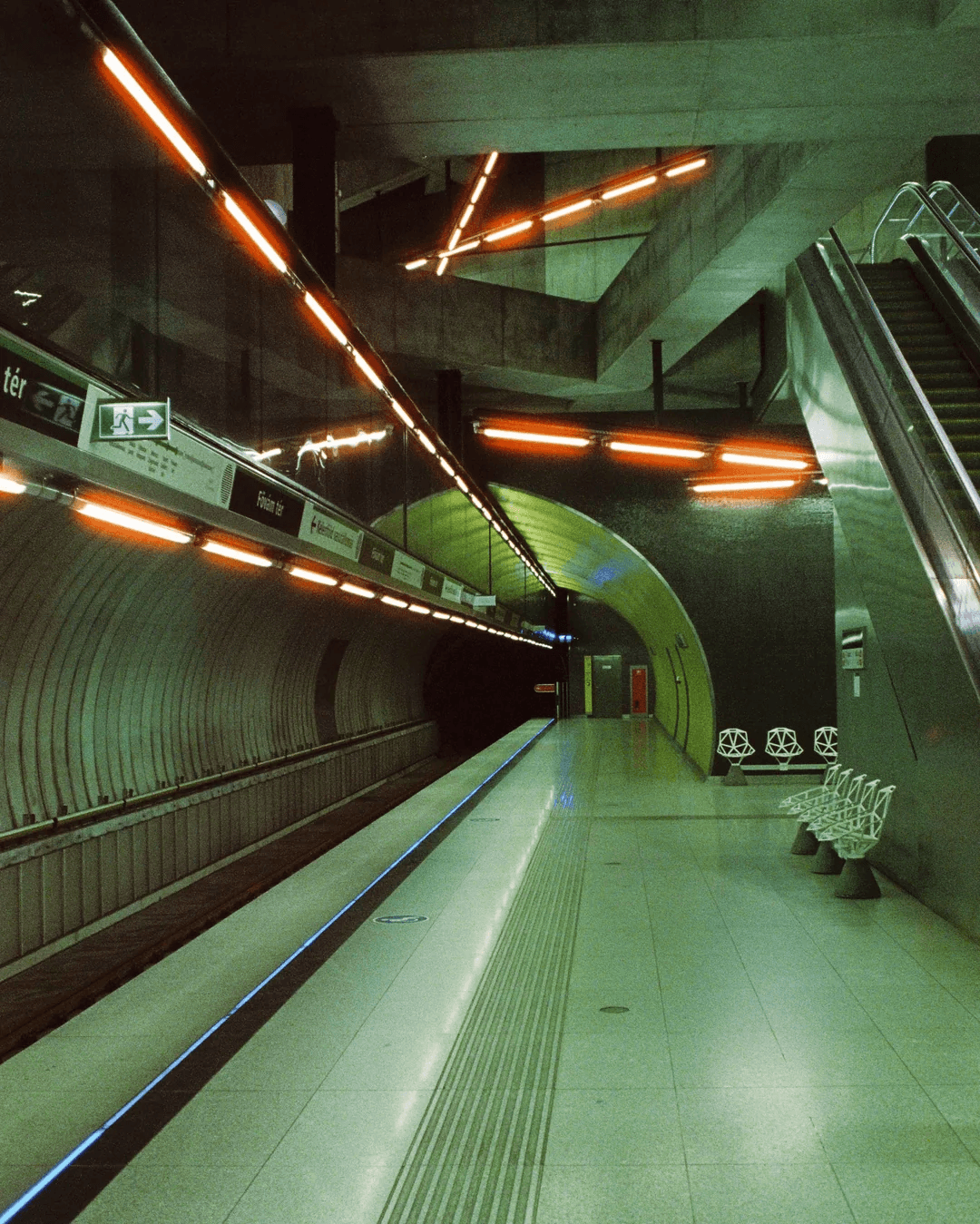 Empty underground metro platform with curved concrete walls and amber tunnel lighting.